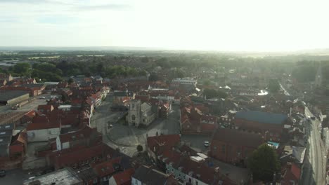 drone shot pushing in to historic english market town centre with church at golden hour sunrise