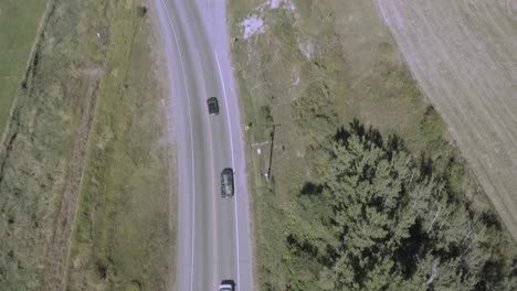 la plataforma rodante aérea pasa por encima de la autopista interestatal con tráfico bidireccional que se bifurca hacia una carretera comercial con cargadores de gatos de madera y camiones de arena industriales abiertos que se dirigen a una ruta comercial