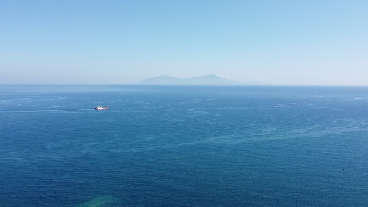 티모르-레스테의 거대한 푸른 바다 위를 떠다니는 드론의 공중 뷰와 멀리 있는 선박과 인기 있는 다이빙 목적지인 아타우로 섬