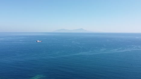 aerial drone view rising over vast blue ocean of timor-leste with shipping vessel and popular dive destination of atauro island in the distance