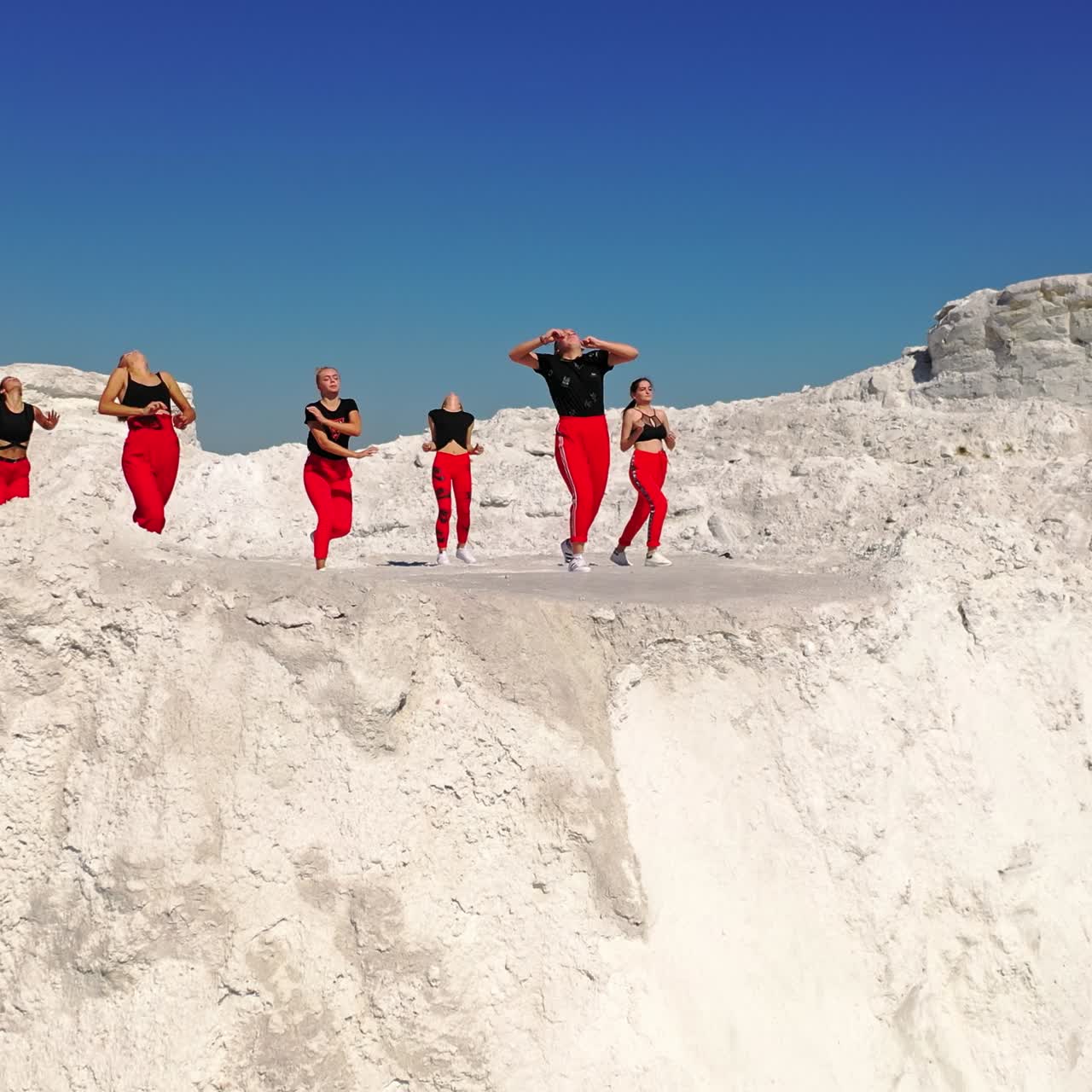 Teenage collective of dancers perform on the white rocks. Drone footage over the girls dancing outdoors
