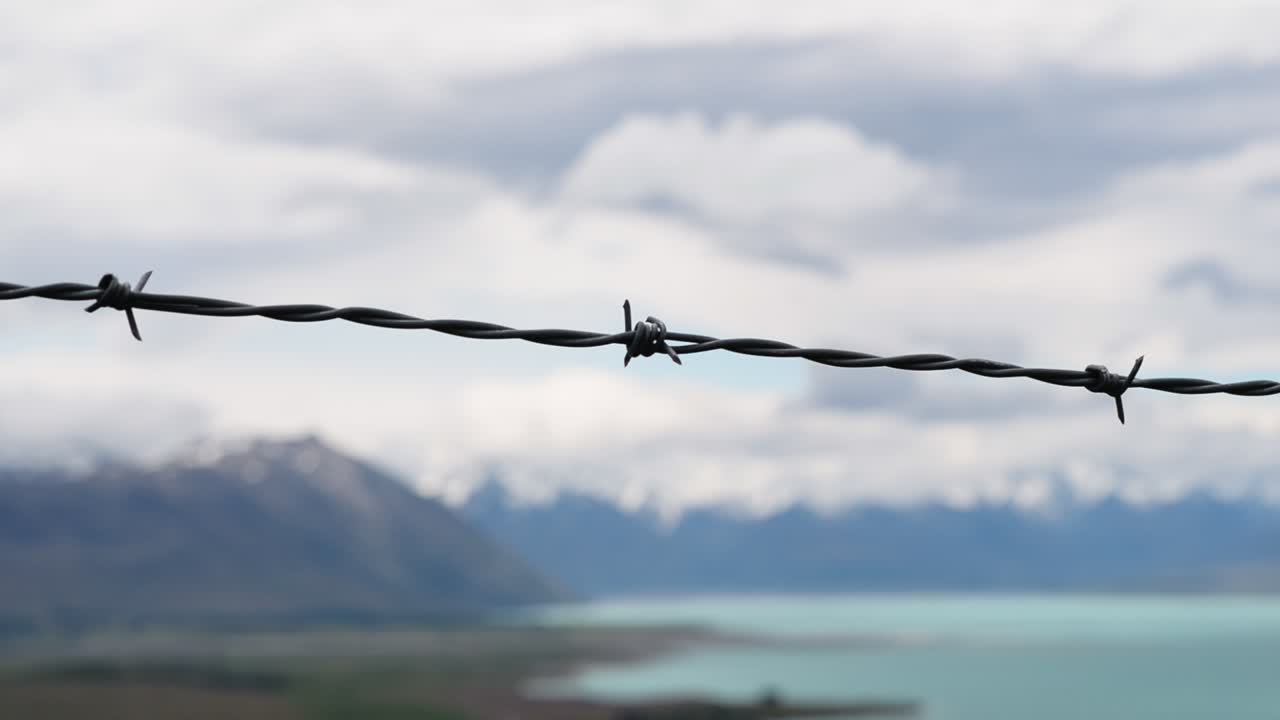 청록색 호수와 멋진 산의 경치가 배경에 있는 철조망의 근접