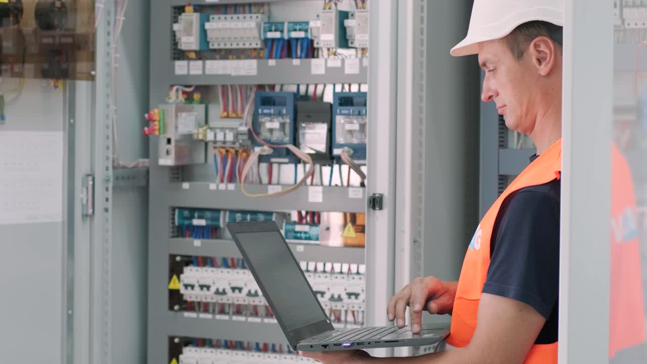 el ingeniero eléctrico que trabaja comprueba la tensión de corriente eléctrica y la sobrecarga en la parte delantera del gabinete del centro de carga o de la unidad de consumo para el mantenimiento en la sala principal del sistema de distribución de energía.