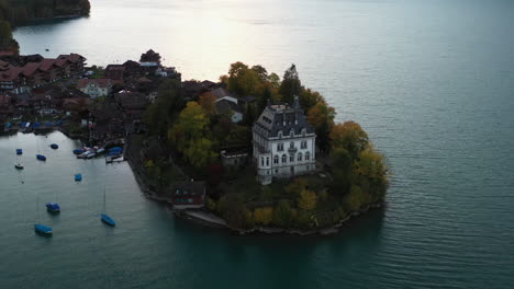 cinematic revealing aerial shot starting on the iseltwald castle then going wide of lake brienz in switzerland