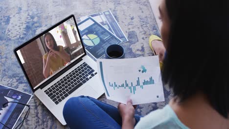 African-american-woman-holding-a-document-having-a-video-call-with-female-colleague-on-laptop