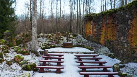 Aerial-approach-toward-church-cross-at-destroyed-religious-place-over-red-bench