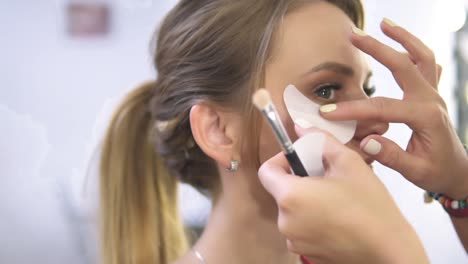 Visagistin-Verwendet-Weiße-Augenklappen,-Um-Haut-Und-Make-up-Beim-Auftragen-Von-Augen-Make-up-Zu-Schützen.-Nahaufnahme