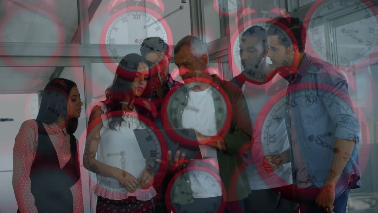 Leader holding tablet, tapping as team leaning in while red alarms pulsing showing project deadline