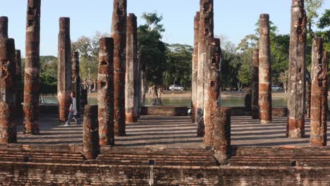 girl walking between stone pillars in sukhothai historical park, central thailand