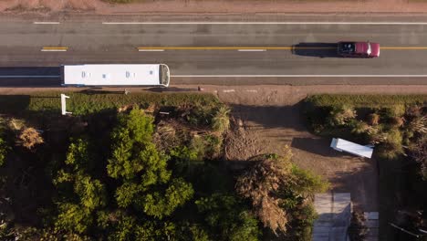 Aerial-top-down-shot-of-passenger-leaving-bus-at-bus-station-during-cars-overtaking-at-sunset---Punta-del-Este,Uruguay