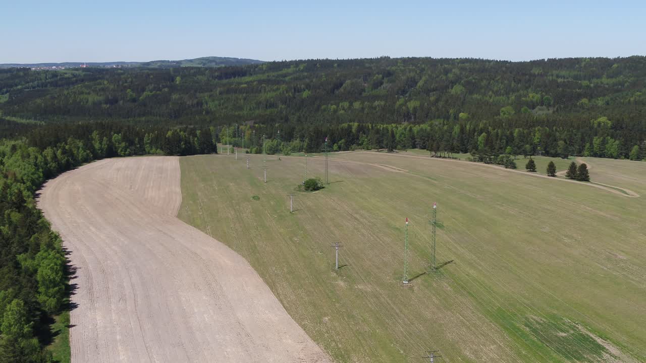 Semi orbit aerial showing a contrast between green grassland and dry farmland under clear blue sky in Czech Republic