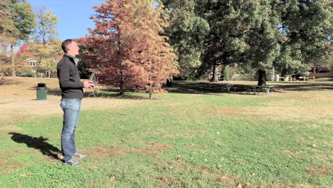 a drone operator flies his drone on a beautiful fall day in the park