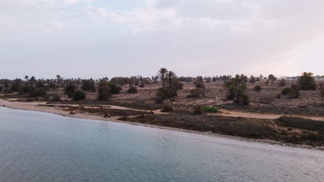 an aerial view of a beach, with the ocean and sandy shoreline visible in the lagoon of djerba at tunisia , atv quad on a dirt pathway that crosses through the area