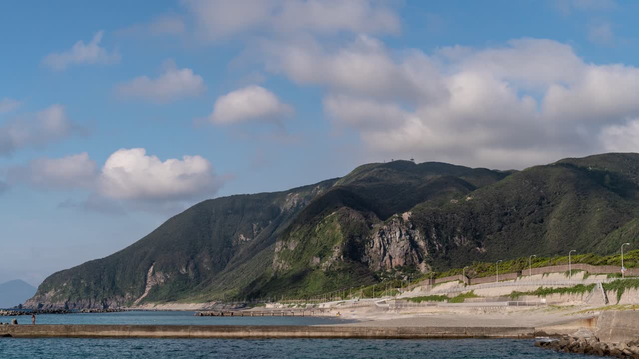전경에 바다와 해변이 있는 녹색 절벽에 빠르게 움직이는 구름 시간 경과 그림자