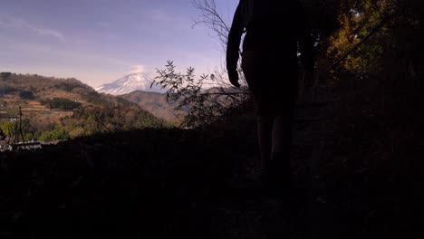 male hiker looking at mount fuji in distance from hill - silhouette shot