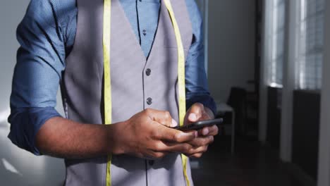 hombre de raza mixta usando un teléfono inteligente en la oficina creativa