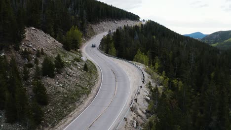 aerial shot of an all terrain vehicle driving up a steep mountain highway in colorado