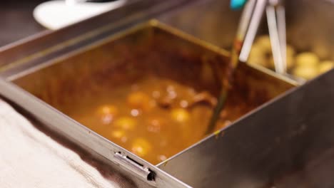 meatballs simmering in sauce at food stall