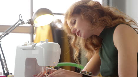 primer plano de una estudiante o propietaria de un negocio que trabaja en la industria de la moda usando una máquina de coser en el estudio