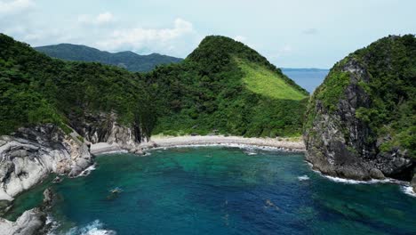 Stunning-Aerial-View-of-tropical-island-cove-with-turquoise-ocean-waters,-lush-jungles-and-rock-formations