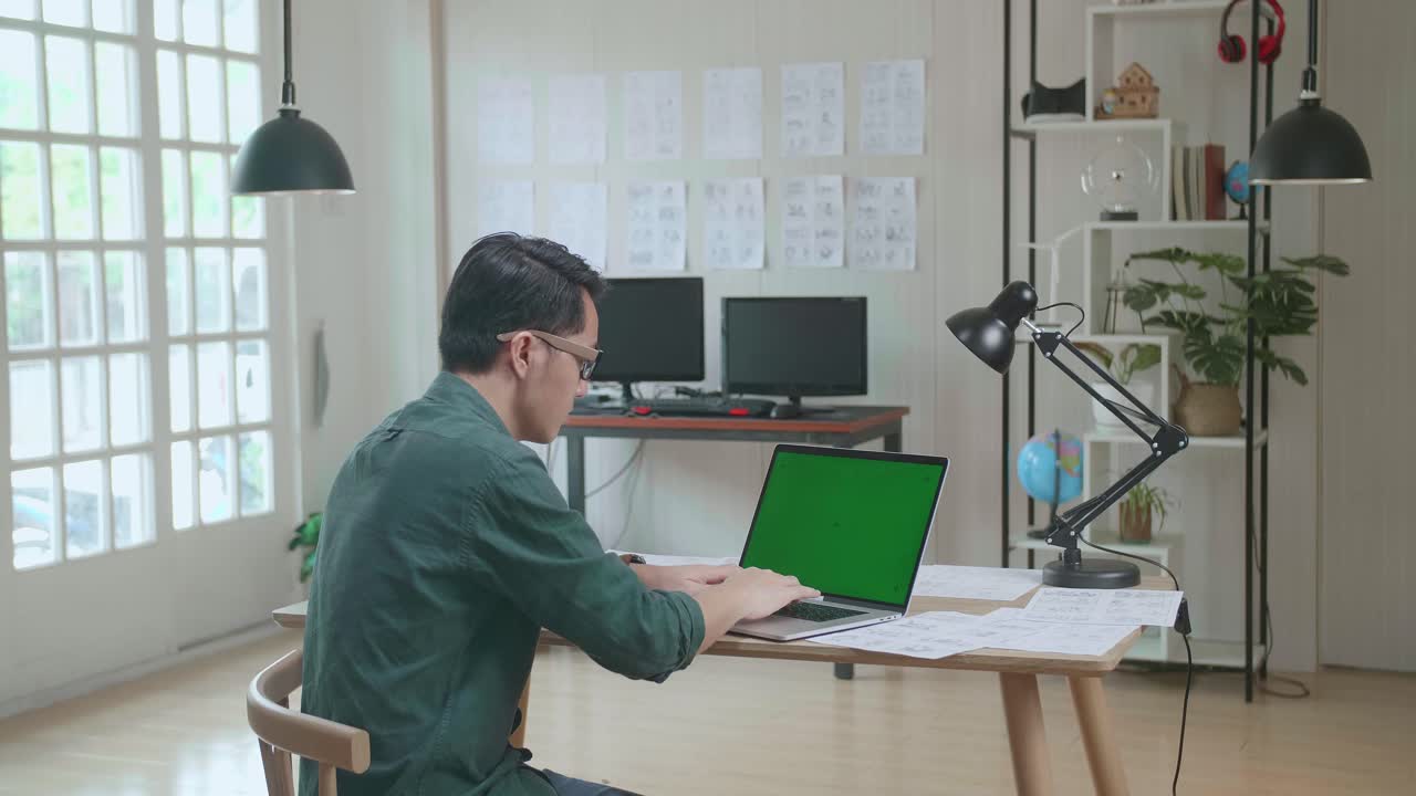 Asian Man Works On Laptop Computer With Mock Up Green Screen Display And Storyboard. Video Editing, Comics Compilation, Application Ui Or Game Plot