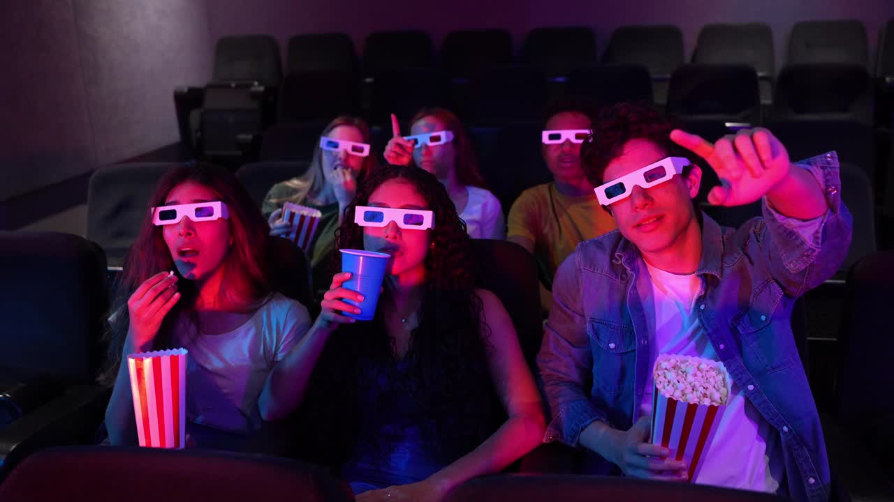 Group of friends enjoying a movie in 3D at the movie theater with popcorn