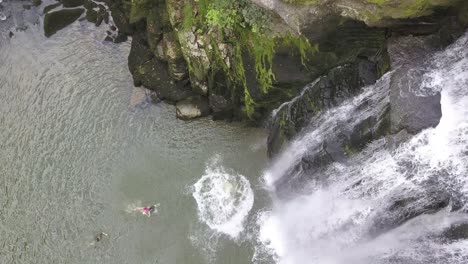 Joven-Atleta-De-Salto-De-Acantilado-Se-Sumerge-Desde-Una-Roca-Junto-A-Una-Cascada-En-El-Río-Doubs,-Neuchatel,-Suiza