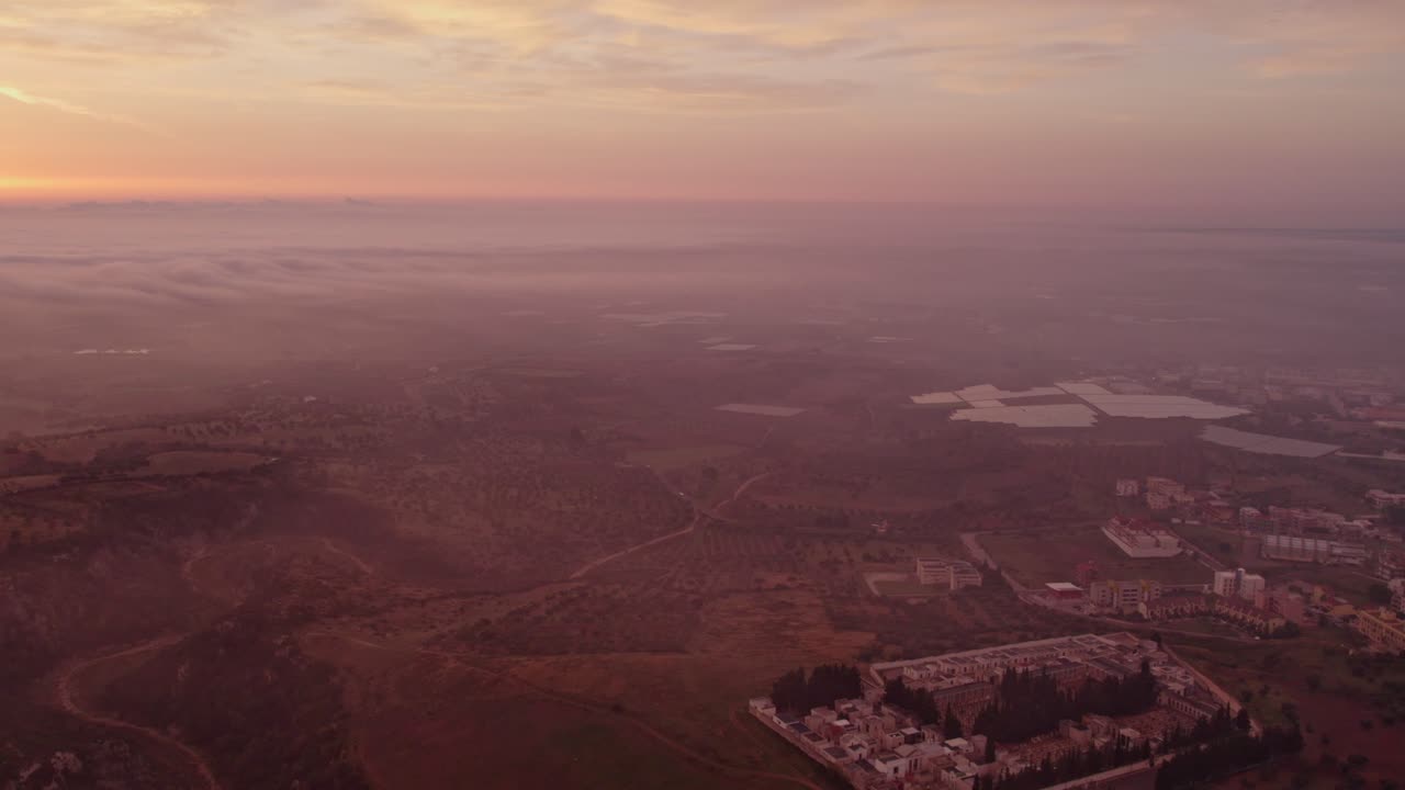 Nascer do sol sobre a cidade de Ginosa, charme urbano nebuloso e sereno