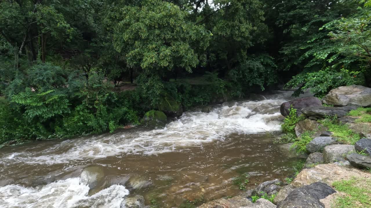 Acqua torbida di un impetuoso fiume di montagna che scorre velocemente durante un temporale in Giappone