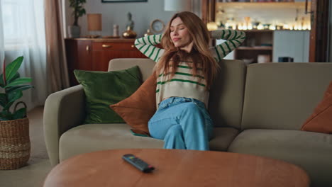 carefree girl relaxing couch at modern living room. happy woman taking cellphone