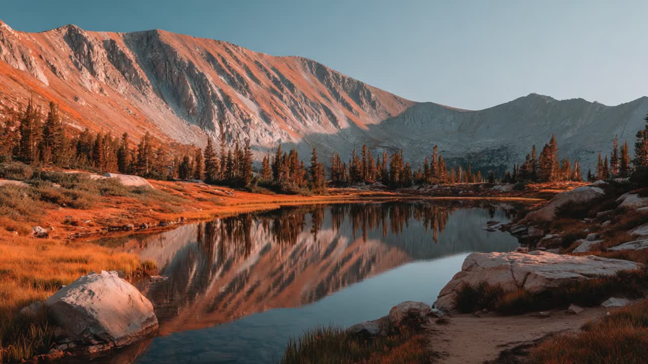 Paesaggio autunnale mozzafiato: montagne maestose che si riflettono su un lago tranquillo, circondato da un fogliame dorato e una fauna selvatica serena in un pittoresco ambiente selvaggio