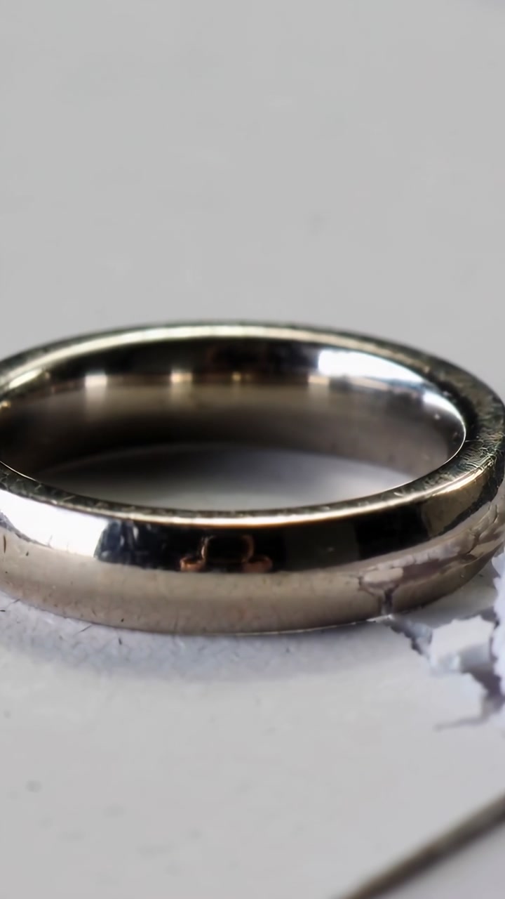 Vertical video: Camera moving down right, showing torn paper edge while ring catching glint