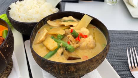 spicy thai coconut soup with chicken, bamboo and vegetables in a beautiful coconut bowl, hot dish in thai cuisine restaurant, 4k shot