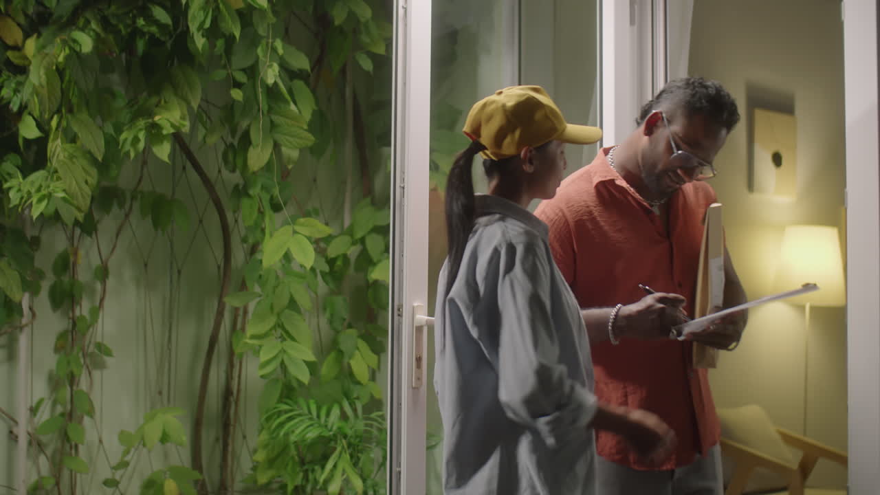 Female Courier Delivering Parcel to Man at Home