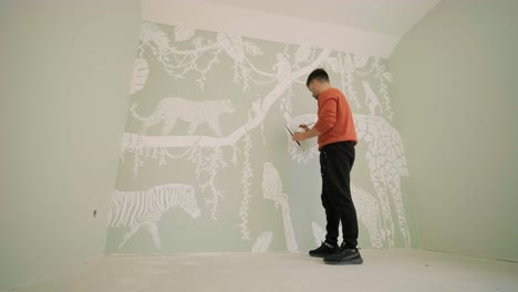 the artist is decorating walls by drawings in the children's room. art painting of the walls in the new house. repair works.