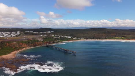 aerial establishing orbit of rocky coastline and cliff walk jetty structure at catherine hill bay, nsw with ocean waves