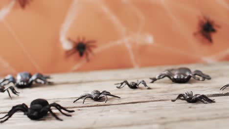Video-of-halloween-spiders-and-spider's-web-and-copy-space-on-wooden-and-orange-background