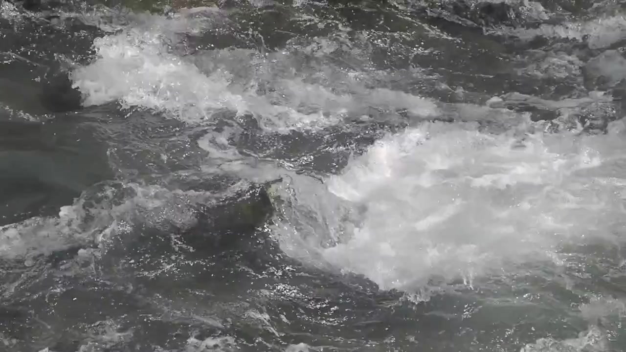 Dynamischer Fluss von turbulentem Flusswasser mit weißem Schaum.