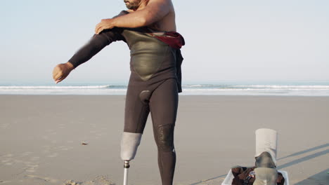 vertical motion of male surfer with artificial leg wearing wetsuit on the beach