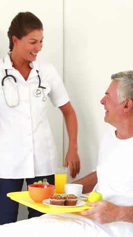 enfermera ofreciendo desayuno a un anciano relajándose en la cama