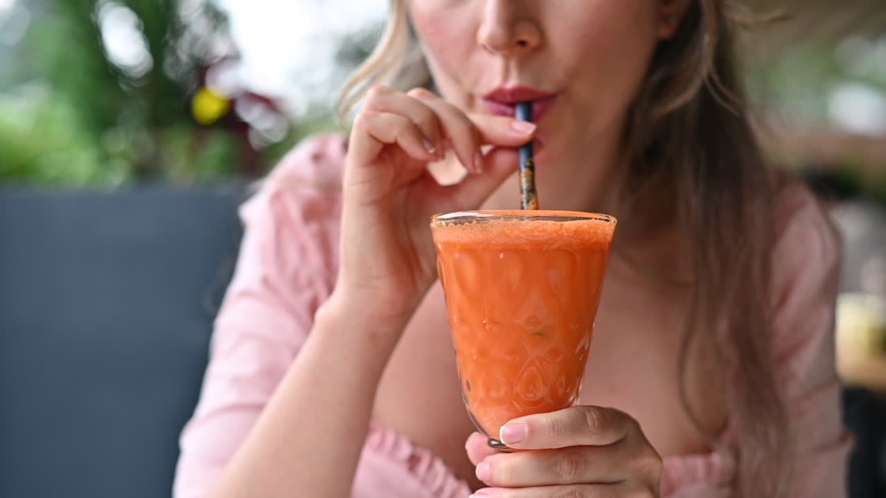Donna bruna che beve succo di carote e arancia in un ristorante