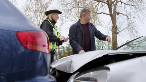 female traffic police officer takes statement from driver on mobile phone at road traffic accident