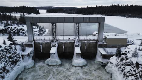 Statisch-Aufsteigende-Drohne-Erschossen-Schneebedeckte-Straße-Mit-Rauschendem-Wasser-Notigi-Wasserkraftwerk-Industrielle-Struktur-In-Der-Arktis