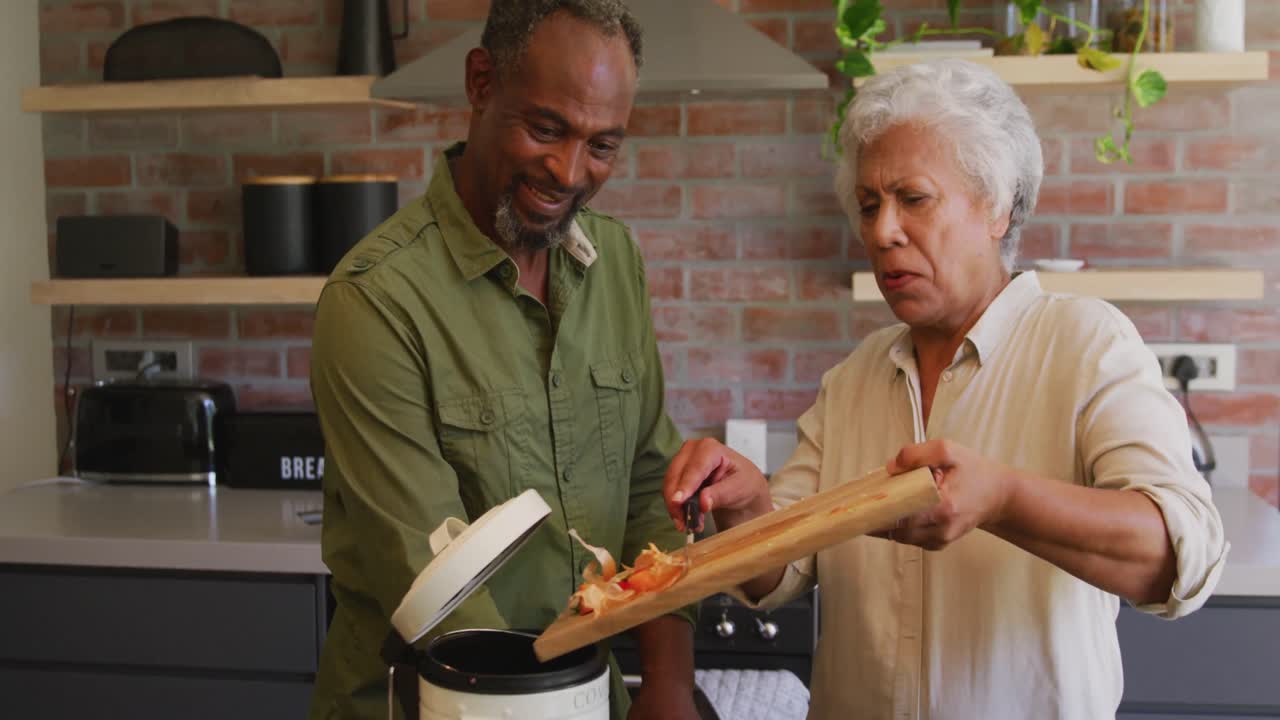 Marito afroamericano anziano e moglie di razza mista che cucinano insieme a casa.