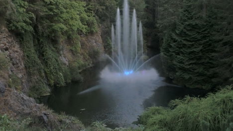 a pan tilt shot reveals multiple streams spouting from a lake as a lighted fountain