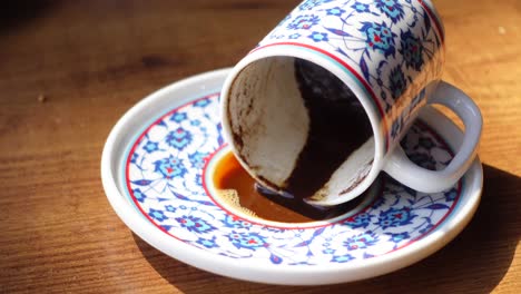 a turkish coffee cup and saucer with coffee grounds