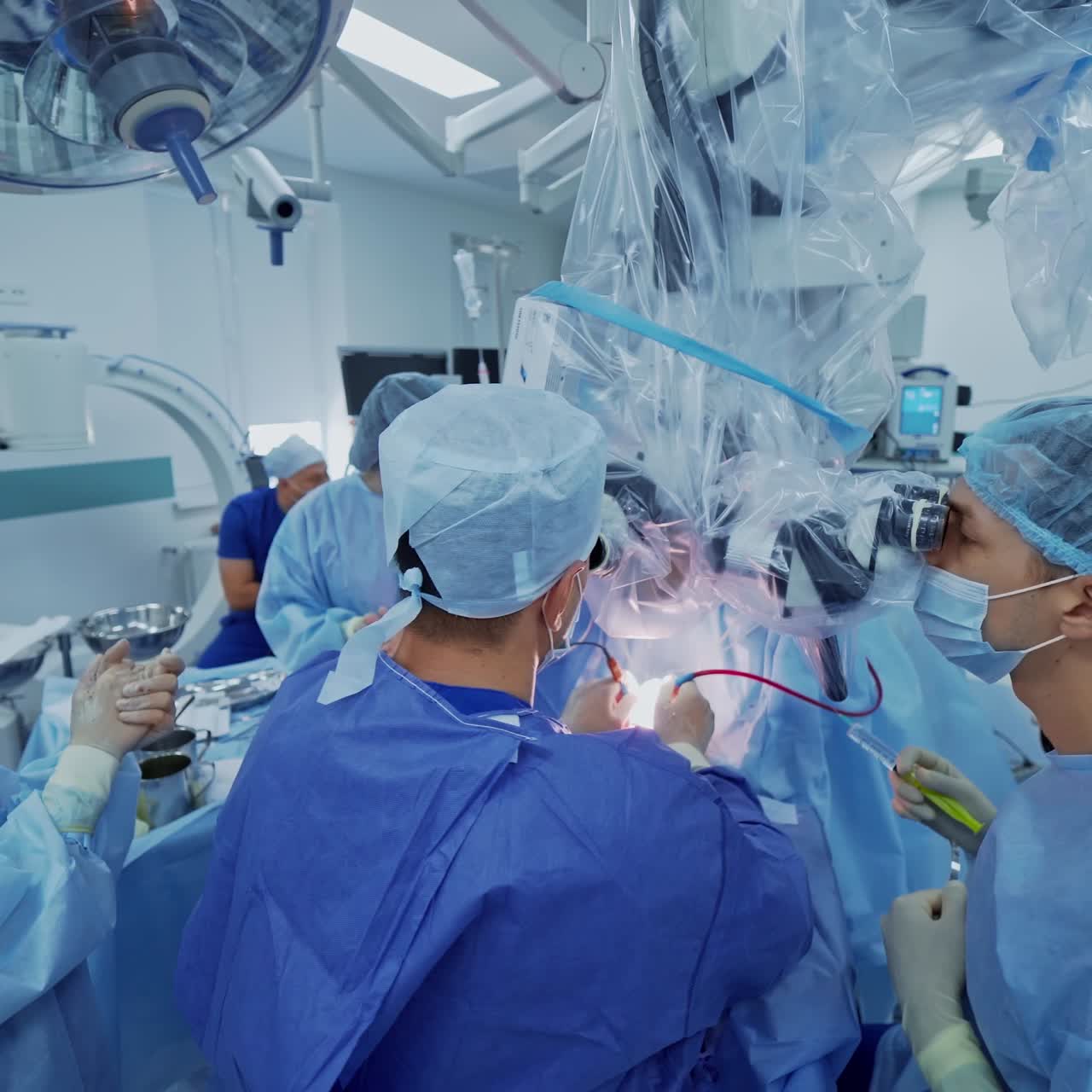 Modern technology in surgery. Team of doctors in medical uniform conduct an operation to a patient while looking into the microscope.