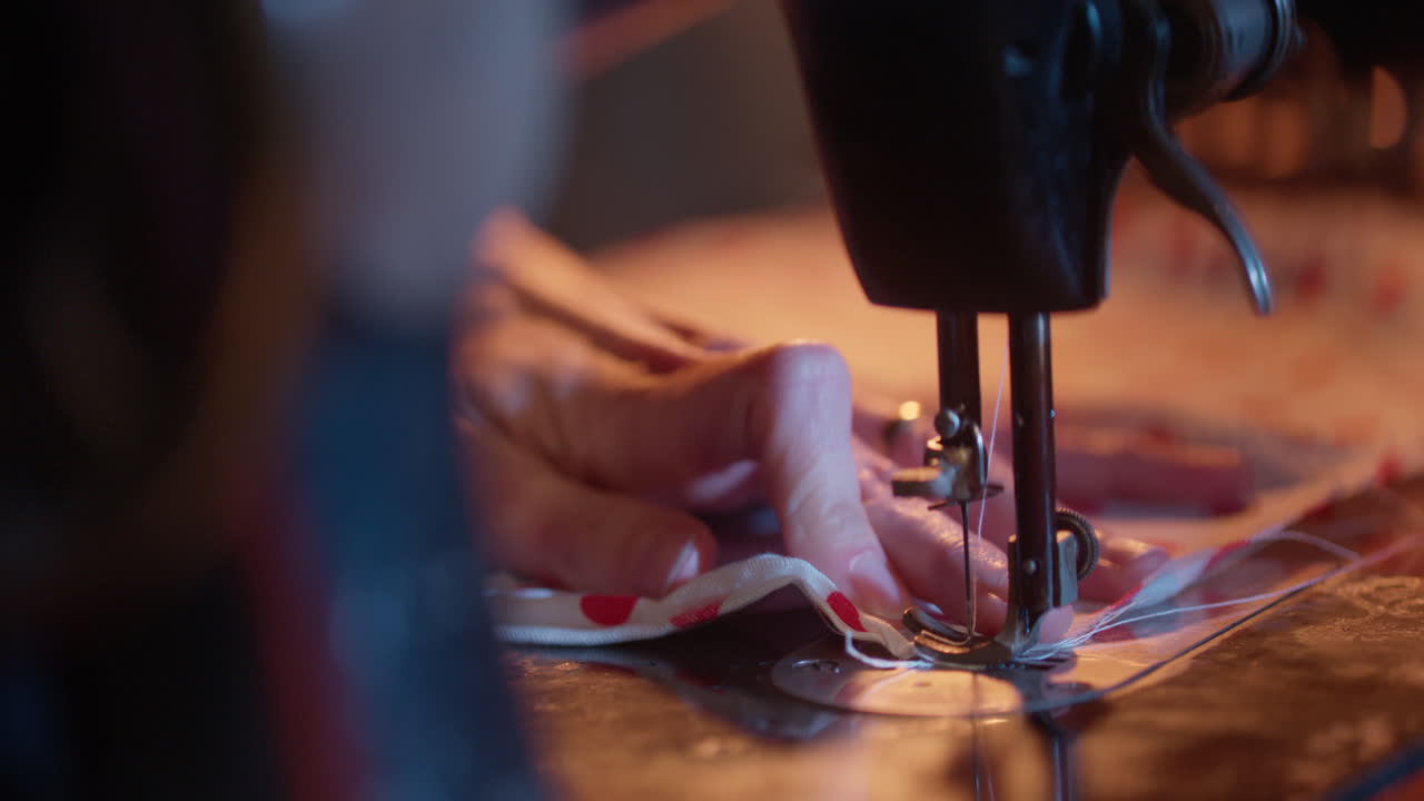 Primo piano di mani che azionano una macchina da cucire vintage