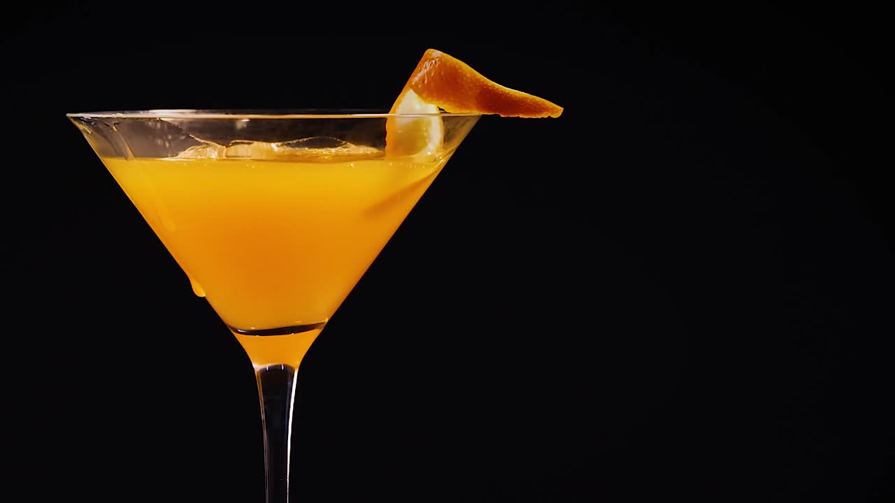 A vibrant orange juice stream fills a glass, garnished with a fresh orange slice against a dark background.