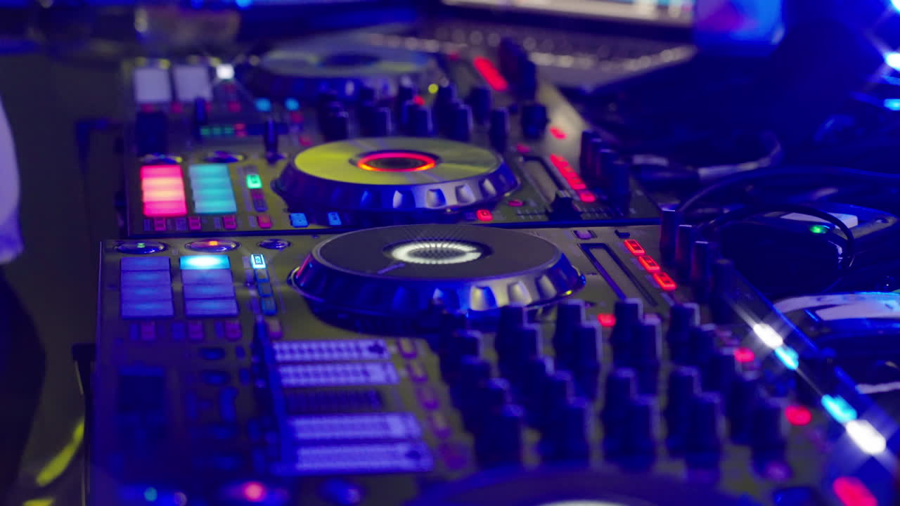 Tangan DJ Mengoperasikan Pengontrol Mixer dengan Lampu Warna-warni di Klub Malam